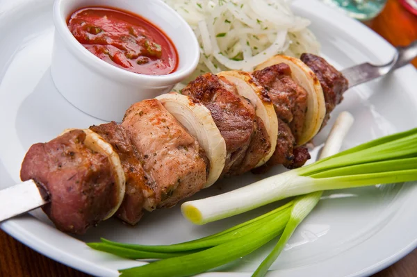 Kebab de shish com molho e verdes em uma chapa — Fotografia de Stock