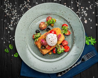 Haşlanmış yumurta, zeytin ve domatesli sosis şnitzel. Karanlık bir arka planda