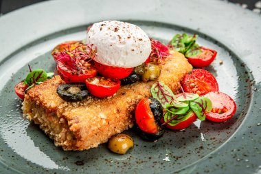 Haşlanmış yumurta, zeytin ve domatesli sosis şnitzel. Karanlık bir arka planda