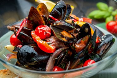 Çeşitli sebzeler, baharatlar ve kıtır ekmeklerle haşlanmış midye servis ediyorlar.