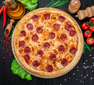 Lezzetli biberli pizza ve siyah beton arka planda domates fesleğeni. Acı biberli pizzanın en iyi manzarası. Metin için kopyalama alanı ile. Düz yatıyordu