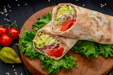 Sebzeli taze tortilla dürümü ve tahta kesme tahtasında somon. Shawarma