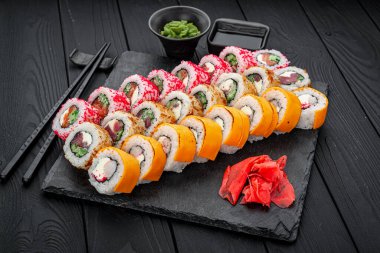 Suşi seti. Philadelphia Roll, California, Unagi, siyah arka planda taze malzemeli siyah ejderha. Suşi menüsü. Japon yemeği..