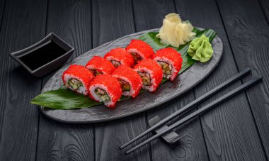 Siyah arka planda geleneksel lezzetli suşi rulosu. Pilavlı suşi, nori, krem peynir, tobiko havyarı, avokado. Suşi menüsü. Japon mutfağı, restoran. Asya yemekleri