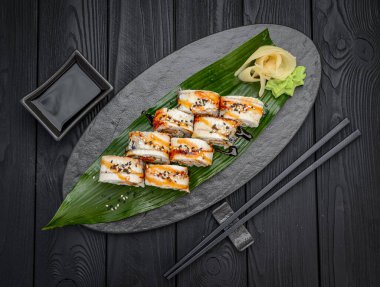 Füme yılan balığı ve karidesli suşi rulo ejderhası. Siyah arka planda geleneksel lezzetli suşi rulosu. Suşi menüsü. Japon mutfağı, restoran. Asya yemekleri
