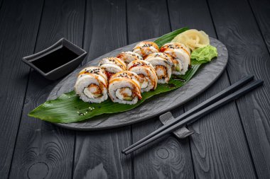 Füme yılan balığı ve karidesli suşi rulo ejderhası. Siyah arka planda geleneksel lezzetli suşi rulosu. Suşi menüsü. Japon mutfağı, restoran. Asya yemekleri