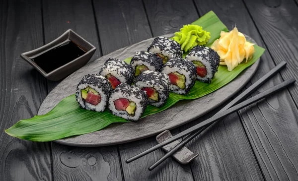 Fresh sushi roll with tuna and black caviar. Traditional delicious fresh sushi roll set on a black background. Sushi roll with rice, nori, cream cheese, tobiko caviar, avocado.
