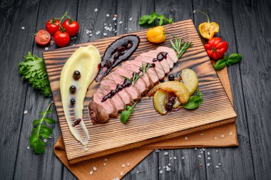 Tahta üzerinde böğürtlen soslu dilimlenmiş biftek. Bir restoranda hizmet veriyor. Restoran menüsü için fotoğraf