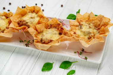 Peynirli, tavuklu ve mantarlı bir sepetin içinde jülyen turtası pişir. Restoranda yemek servisi. Menü için fotoğraf