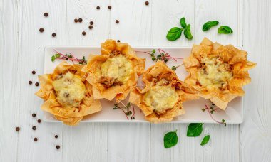 Peynirli, tavuklu ve mantarlı bir sepetin içinde jülyen turtası pişir. Restoranda yemek servisi. Menü için fotoğraf