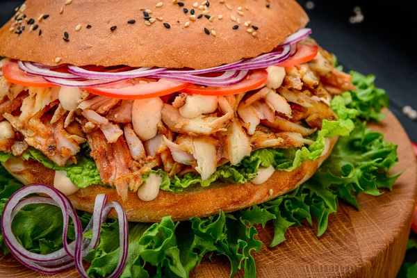 Sandwich with grilled chicken and vegetables. Burger. Big sandwich with chicken meat, sauce, tomatoes, onions. Photo for the menu