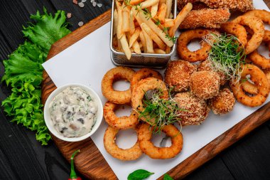 Mozarella toplarını, kalamar halkalarını, soğan halkalarını, patates kızartmalarını, tavuk nuggetlarını ve sosu çıkarın.