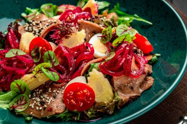 Taze sebzeli sığır dili salatası, soğan turşusu ve bir tabakta mini mısır..