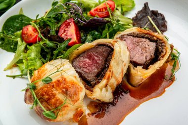 Wellington usulü sığır eti, klasik biftek, yeşil salatalı klasik tarif. Restoranda yemek servisi. Sağlıklı gıda konsepti. Menü için fotoğraf