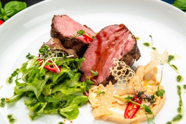 Salata ve humus ile dana madalyonu. Restoranda yemek servisi. Sağlıklı gıda konsepti. Menü için fotoğraf