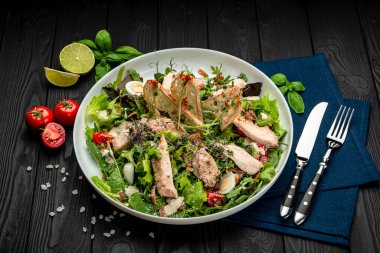 Siyah ahşap masada beyaz tabakta taze sezar salatası. Üst Manzara. Restoranda yemek servisi. Sağlıklı gıda konsepti. Menü için fotoğraf
