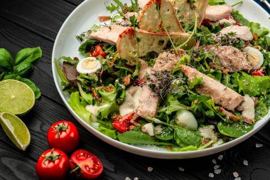 Siyah ahşap masada beyaz tabakta taze sezar salatası. Üst Manzara. Restoranda yemek servisi. Sağlıklı gıda konsepti. Menü için fotoğraf