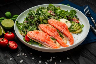 Taze salata ve ahşap arka planda krem peynirli kızarmış somon balığı. Sağlıklı gıda konsepti.