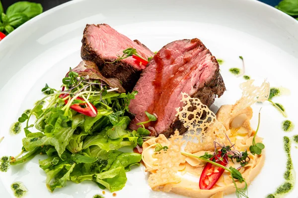 Salata ve humus ile dana madalyonu. Restoranda yemek servisi. Sağlıklı gıda konsepti. Menü için fotoğraf