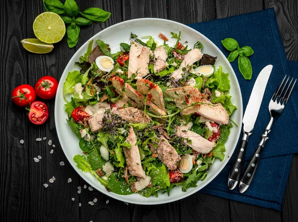 Siyah ahşap masada beyaz tabakta taze sezar salatası. Üst Manzara. Restoranda yemek servisi. Sağlıklı gıda konsepti. Menü için fotoğraf