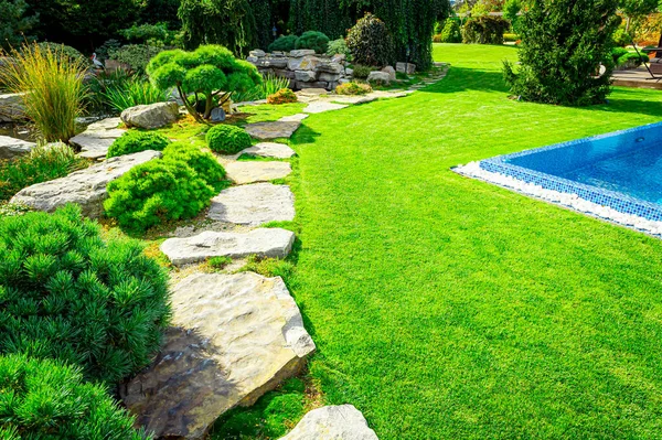 フロントヤード 家の後ろに明るい緑の芝生と交差する多色の低木と景観デザインは 現代的な庭のケアサービス 背景のための美しい庭と緑の草です — ストック写真