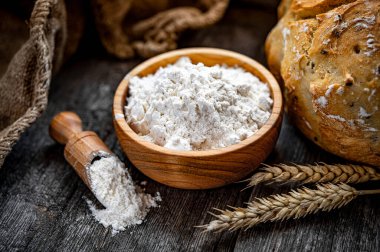 Eski ahşap bir masada ev yapımı ekmeğin üzerinde buğday unu.