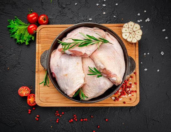 Raw chicken thigh on black background.