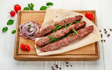 Ahşap bir tahtanın üzerinde baharatlı ızgara Lula kebabı. Restoranda yemek servisi. Menü için fotoğraf