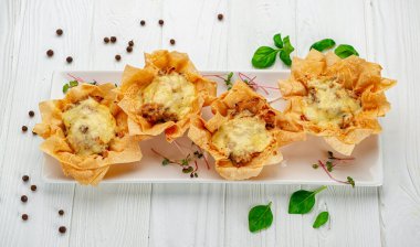 Peynirli, tavuklu ve mantarlı bir sepetin içinde jülyen turtası pişir. Restoranda yemek servisi. Menü için fotoğraf