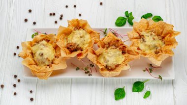 Peynirli, tavuklu ve mantarlı bir sepetin içinde jülyen turtası pişir. Restoranda yemek servisi. Menü için fotoğraf