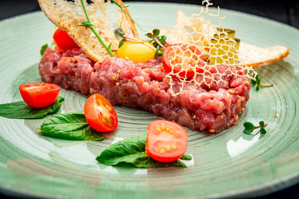Beef steak tartare with raw egg yolk. French cuisine. Top view. Healthly food. Serving food in a restaurant