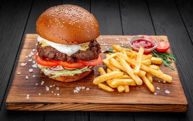Siyah arka planda kızarmış patatesli bir Amerikan hamburgeri..