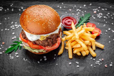 Siyah arka planda kızarmış patatesli bir Amerikan hamburgeri..