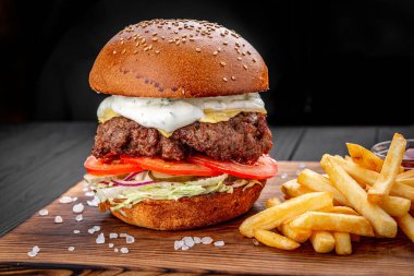 Siyah arka planda kızarmış patatesli bir Amerikan hamburgeri..