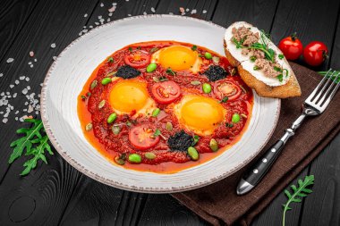 Siyah havyarlı Shakshuka yumurtaları, ton balıklı kızarmış ekmek.