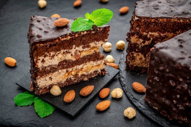 Fındıklı, fındıklı ve bademli karamel çikolatalı tart. Siyah arka planda cevizli çikolatalı pasta.