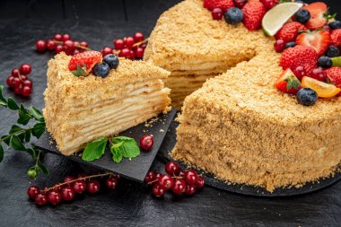 Böğürtlen ve meyvelerle süslenmiş Napolyon keki. Koyu arkaplanda nefis ev yapımı tatlı..