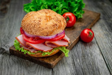 Eski ahşap bir masada jambonlu ve sebzeli sandviç. Basit öğle yemeği.