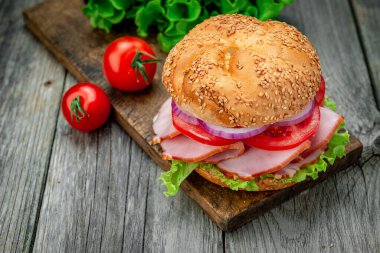 Eski ahşap bir masada jambonlu ve sebzeli sandviç. Basit öğle yemeği.
