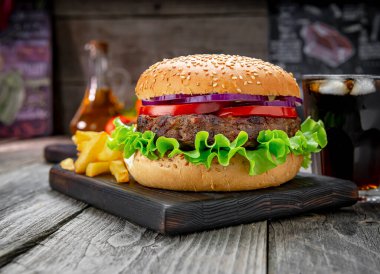 Domatesli ızgara sığır burger, soğan ve kızarmış patates. Restoranda nefis ızgara yemekler.
