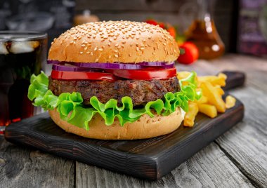 Domatesli ızgara sığır burger, soğan ve kızarmış patates. Restoranda nefis ızgara yemekler.