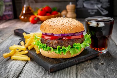 Domatesli ızgara sığır burger, soğan ve kızarmış patates. Restoranda nefis ızgara yemekler.