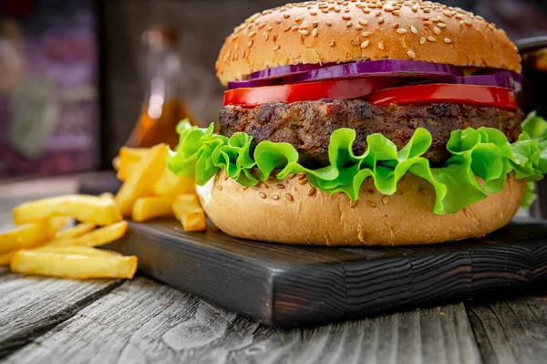 Domatesli ızgara sığır burger, soğan ve kızarmış patates. Restoranda nefis ızgara yemekler.