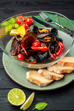 Çeşitli sebzeler, baharatlar ve kıtır ekmeklerle haşlanmış midye servis ediyorlar.