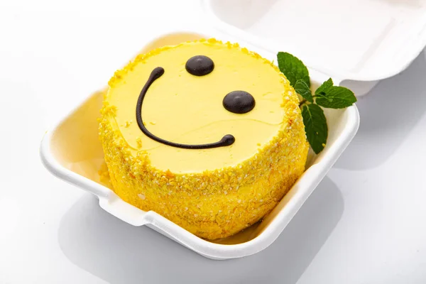 Bento cake with smiley face pattern and hearts in plastic box-packaging. lemon cake