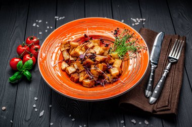 Koyu arkaplanda renkli bir tabakta kızarmış patlıcan parçaları. Restoranda yemek servisi..