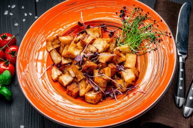 Koyu arkaplanda renkli bir tabakta kızarmış patlıcan parçaları. Restoranda yemek servisi..