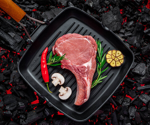 Raw beef steak on the grill pan, on burning charcoal barbeque