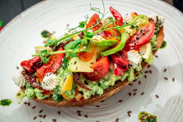 Bruschetta with sun-dried tomatoes, cream cheese, avocado and fresh vegetables. Healthy and wholesome food. Serving food in a restaurant. Photo for the menu.