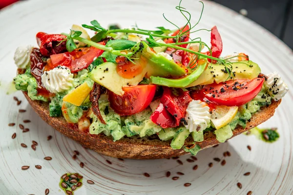 Bruschetta with sun-dried tomatoes, cream cheese, avocado and fresh vegetables. Healthy and wholesome food. Serving food in a restaurant. Photo for the menu.